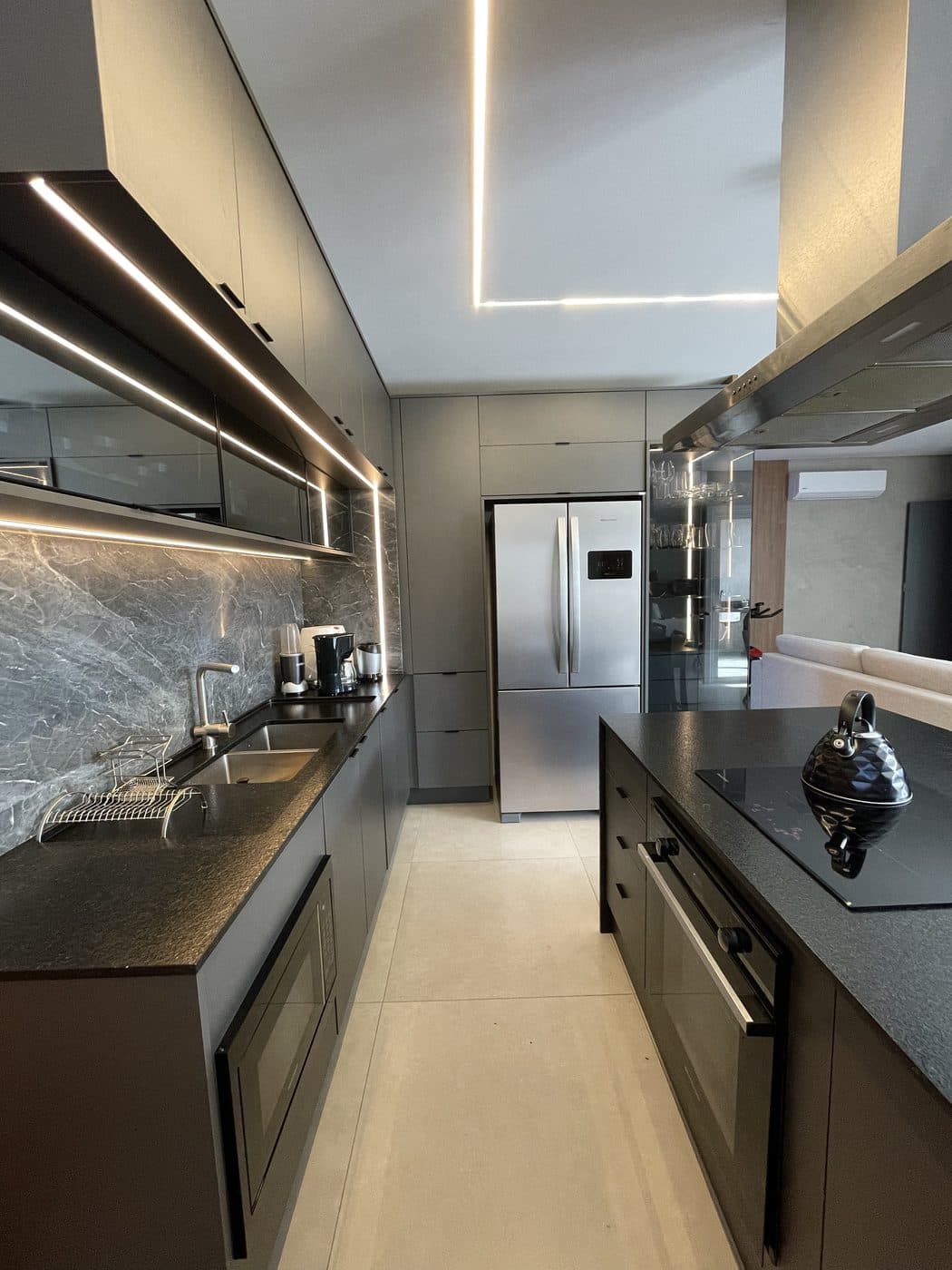 Cozinha planejada pela Comar Móveis Planejados, com acabamento escuro e iluminação linear